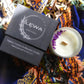 Top view of 'Confidence' Candle with dried floral decoration on top, beside the LEWA black signature box on patterned fabric.